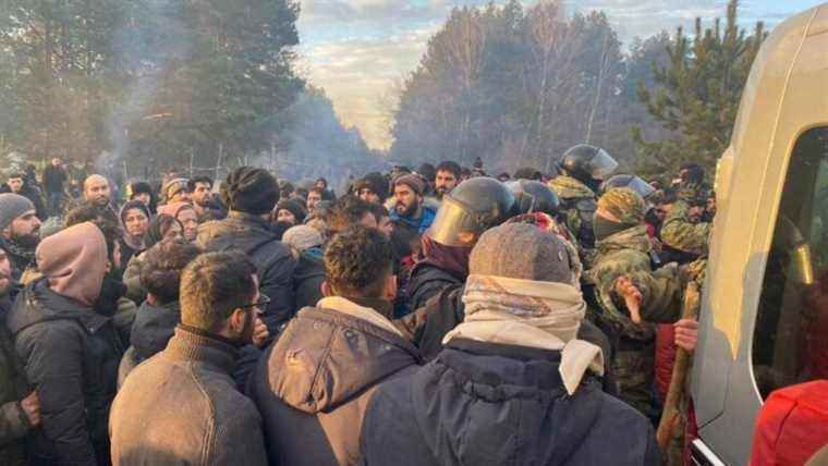 a crowd of migrants mass at a border post with Poland