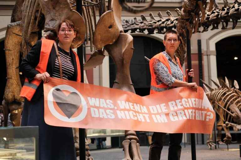 Germany |  Two environmental activists cling to a dinosaur skeleton in a museum