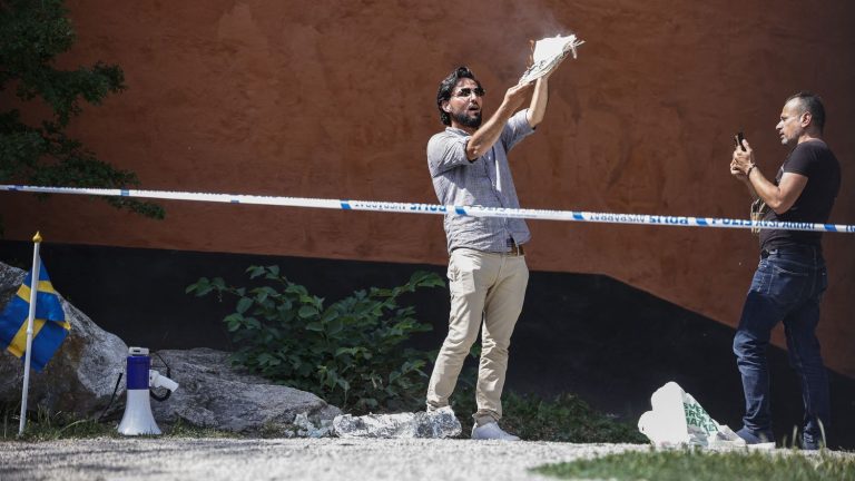 a man burns pages from a copy of the Koran in front of a mosque