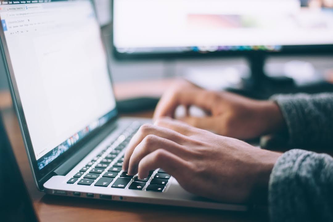 A person typing on a laptop sending a HIPAA fax.