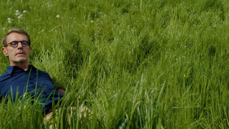 Lambert Wilson driving a tractor in an extravagant road movie