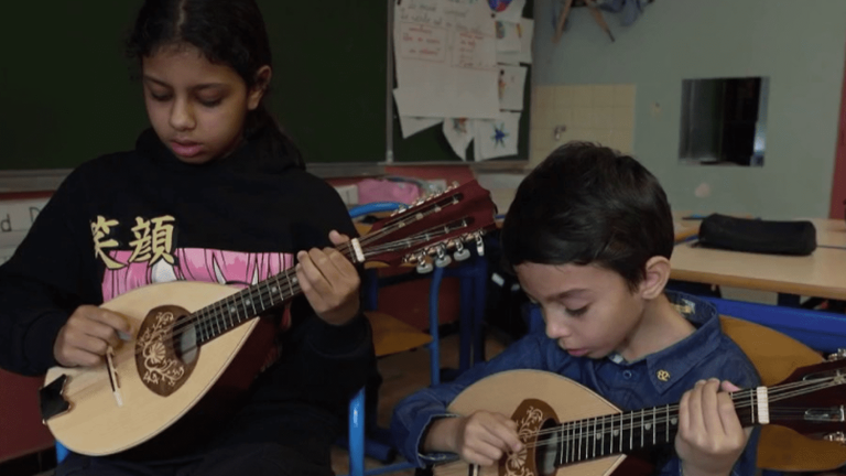 a musician teaches the mandolin to children in the northern neighborhoods