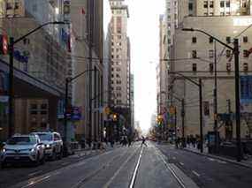 Les piétons traversent l'intersection de Bay Street et Wellington Street West dans le quartier financier de Toronto, le jeudi 25 mars 2021.