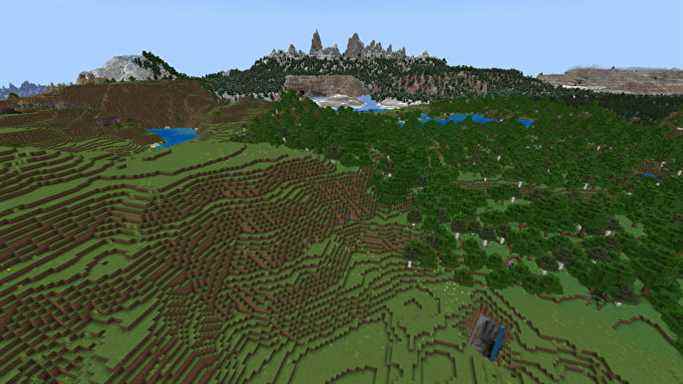 Un paysage vallonné de Minecraft avec des plaines à gauche, une forêt à droite et de hautes montagnes enneigées en arrière-plan.