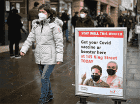 Une femme passe devant un panneau à l'extérieur d'un centre de vaccination COVID-19 à Londres, en Angleterre.