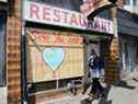 Un homme portant un masque de protection passe devant un restaurant barricadé lors de l'épidémie mondiale de la maladie à coronavirus à Toronto le 6 avril 2020. 