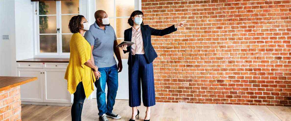 Agent immobilier et client en masque facial regardant un nouveau projet