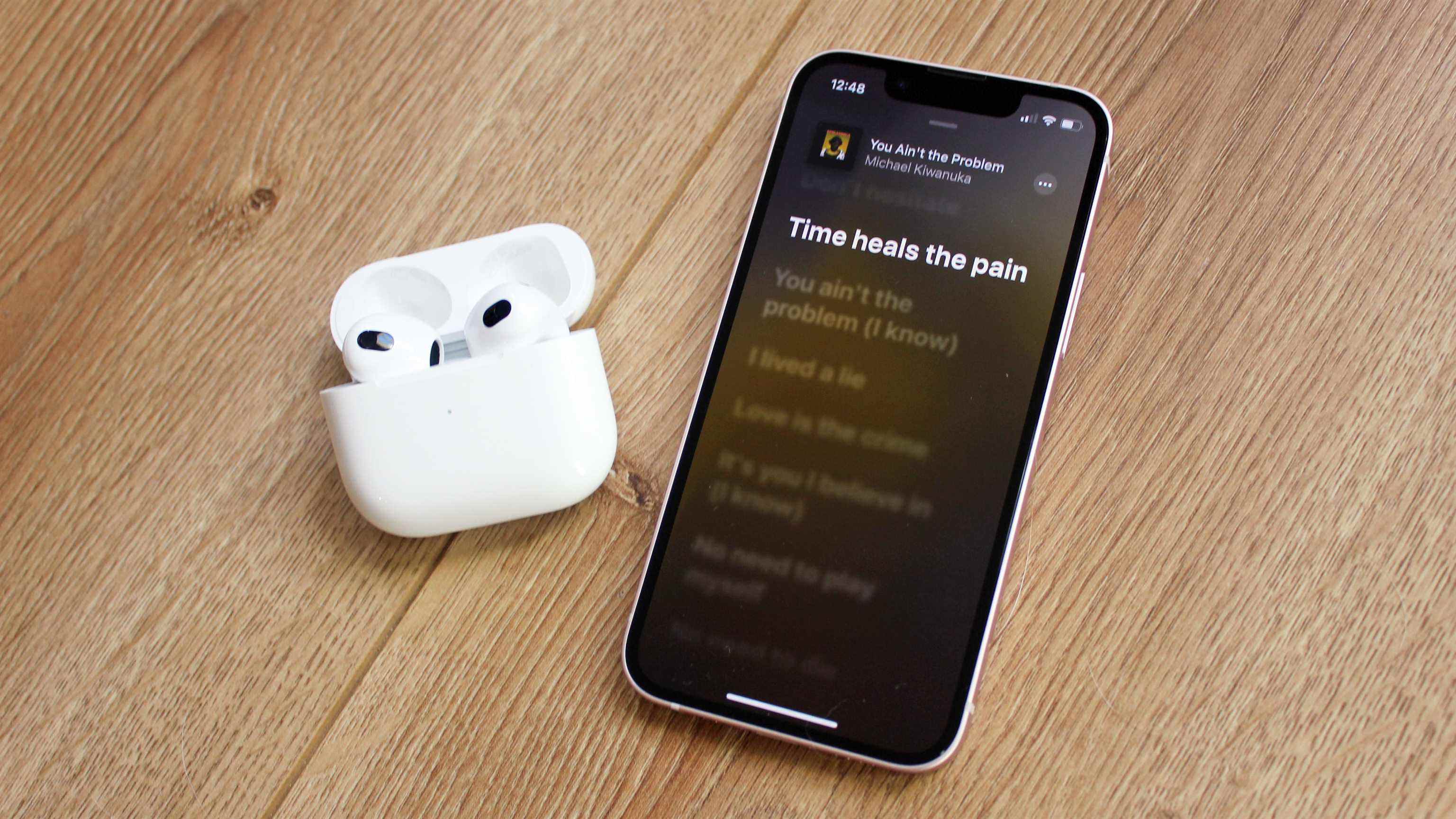 les airpods 3 à côté d'un iphone jouant de la musique apple