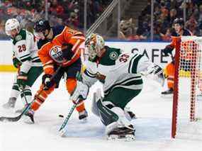 Zach Hyman #18 des Oilers d'Edmonton se bat contre Dmitry Kulikov #29 et le gardien Cam Talbot #33 du Wild du Minnesota au cours de la deuxième période à Rogers Place le 7 décembre 2021 à Edmonton, Canada.