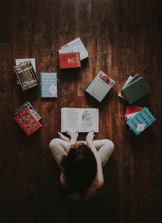 Personne lisant des livres sur un plancher en bois |  Comment protéger vos livres des bogues |  RéserverRiot.com