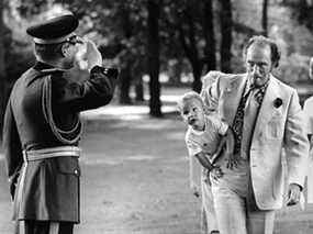 Pierre Trudeau porte le tout-petit Justin Trudeau devant un gendarme en train de saluer en 1973.