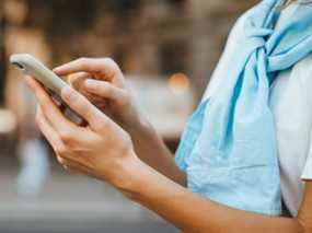 Photo en gros plan de mains féminines avec smartphone.  Jeune femme tapant sur un téléphone mobile dans une rue