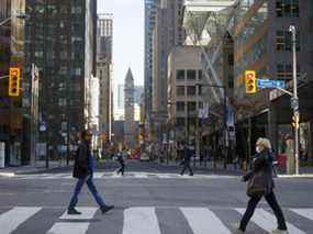 Les navetteurs du matin traversent la rue Yonge à la rue Bay dans le quartier financier de Toronto.