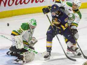 Le gardien de but des Knights Brett Brochu regarde une rondelle déviée après avoir effectué un arrêt de bâton avec Carey Terrance des Erie Otters campé devant le filet des Knights tout en étant mis en échec par Isaiah George lors d'un match le vendredi 3 octobre 2021 au Budweiser Gardens à Londres.  Brochu a effectué 32 arrêts dans la victoire de 4-1 des Knights.  (Mike Hensen/The London Free Press)