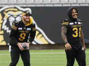 Le quart-arrière des Tiger-Cats Dane Evans et le porteur de ballon Sean Thomas Erlington (31 ans) rient lors de l'entraînement de samedi.