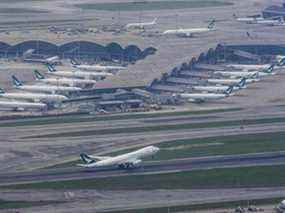 Dans cette photo d'archive prise le 24 avril 2020, des avions de passagers Cathay Pacific sont stationnés sur le tarmac alors qu'un avion Cathay Pacific Cargo (en bas) décolle à l'aéroport international Chek Lap Kok de Hong Kong à Hong Kong.