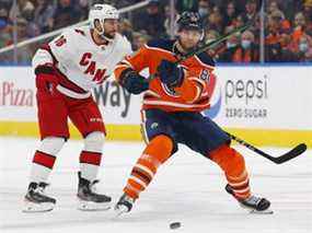 Les défenseurs des Oilers d'Edmonton Markus Neimelainen (80) et l'attaquant des Hurricanes de la Caroline Vincent Trocheck (16 ans) poursuivent une rondelle libre au cours de la première période à Rogers Place.