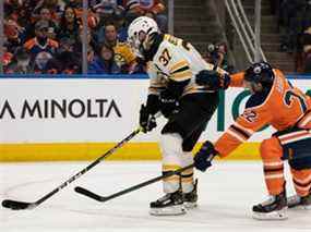 Darnell Nurse (25 ans) des Oilers d'Edmonton affronte Patrice Bergeron (37 ans) des Bruins de Boston lors de la deuxième période de la LNH au Rogers Place à Edmonton, le jeudi 9 décembre 2021.