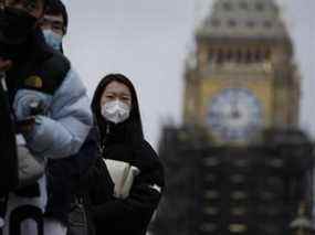 Les gens font la queue pour obtenir un rappel de coronavirus à l'hôpital St Thomas, sur fond de l'échafaudage Elizabeth Tower, connue sous le nom de Big Ben, et du Parlement, à Londres, le lundi 13 décembre 2021. De longues files d'attente se sont formées dans les centres de vaccination de La Grande-Bretagne alors que les gens ont répondu à l'appel du gouvernement pour que tous les adultes reçoivent des injections de rappel pour se protéger contre la variante omicron du coronavirus, dont le Premier ministre a déclaré lundi qu'il avait causé au moins un décès.