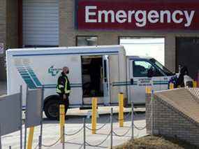 Un travailleur de la santé aide à décharger un véhicule de service de civière à l'Hôpital Saint-Boniface de Winnipeg le 1er novembre 2020.