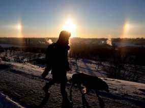 Un piéton passe devant un sundog qui surplombe la vallée de la rivière d'Edmonton, le vendredi 17 décembre 2021.