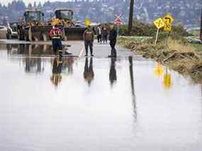 Les gens regardent la crue des eaux venant des États-Unis dans le village de Huntington à Abbotsford, en Colombie-Britannique, le 29 novembre 2021.