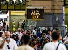 Une signalisation est visible devant la gare de Flinders Street alors que les gens passent lors des célébrations du Nouvel An le 31 décembre 2021 à Melbourne, en Australie.