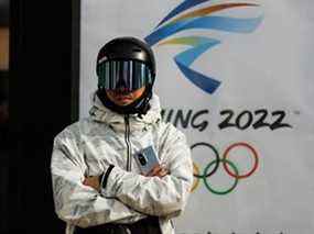 Un snowboarder se tient devant le logo des Jeux olympiques d'hiver de Beijing 2022 à Zhangjiakou, dans la province du Hebei, en Chine, le 20 novembre 2021. Le Canada devrait se joindre aux États-Unis dans un boycott diplomatique des Jeux, écrit Tasha Kheiriddin.