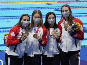 Kylie Masse du Canada, de gauche à droite, Sydney Pickrem, Maggie Mac Neil et Penny Oleksiak célèbrent une médaille de bronze lors de la finale du relais 4 x 100 m quatre nages féminin lors des Jeux olympiques d'été de Tokyo, à Tokyo, le dimanche 1er août 2021.