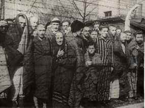 Des survivants de l'Holocauste se tiennent derrière une clôture en fil de fer barbelé après la libération du camp d'extermination nazi allemand d'Auschwitz-Birkenau en 1945 dans la Pologne occupée par les nazis, sur cette photo obtenue par Reuters le 19 janvier 2020. (Avec l'aimable autorisation des archives de Yad Vashem)