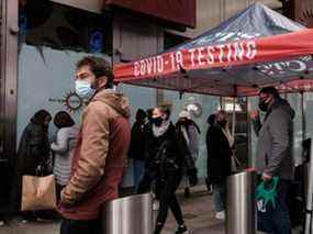 Des groupes de personnes font la queue pour se faire tester pour COVID-19 à Times Square à New York, le dimanche 5 décembre 2021.