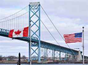 Des drapeaux canadien et américain flottent près du pont Ambassador au poste frontalier Canada-États-Unis à Windsor, en Ontario.  le 21 mars 2020.