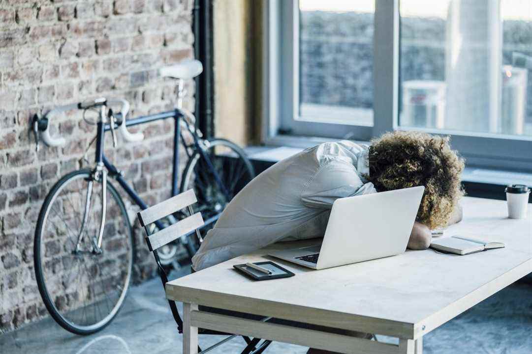 Un employé de bureau avec la tête baissée sur une table de travail.