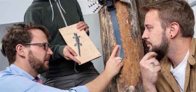 Ardian Jusufi (à gauche) et Rob Siddall (à droite) avec un robot inspiré du gecko sur un tronc d'arbre dans le laboratoire.