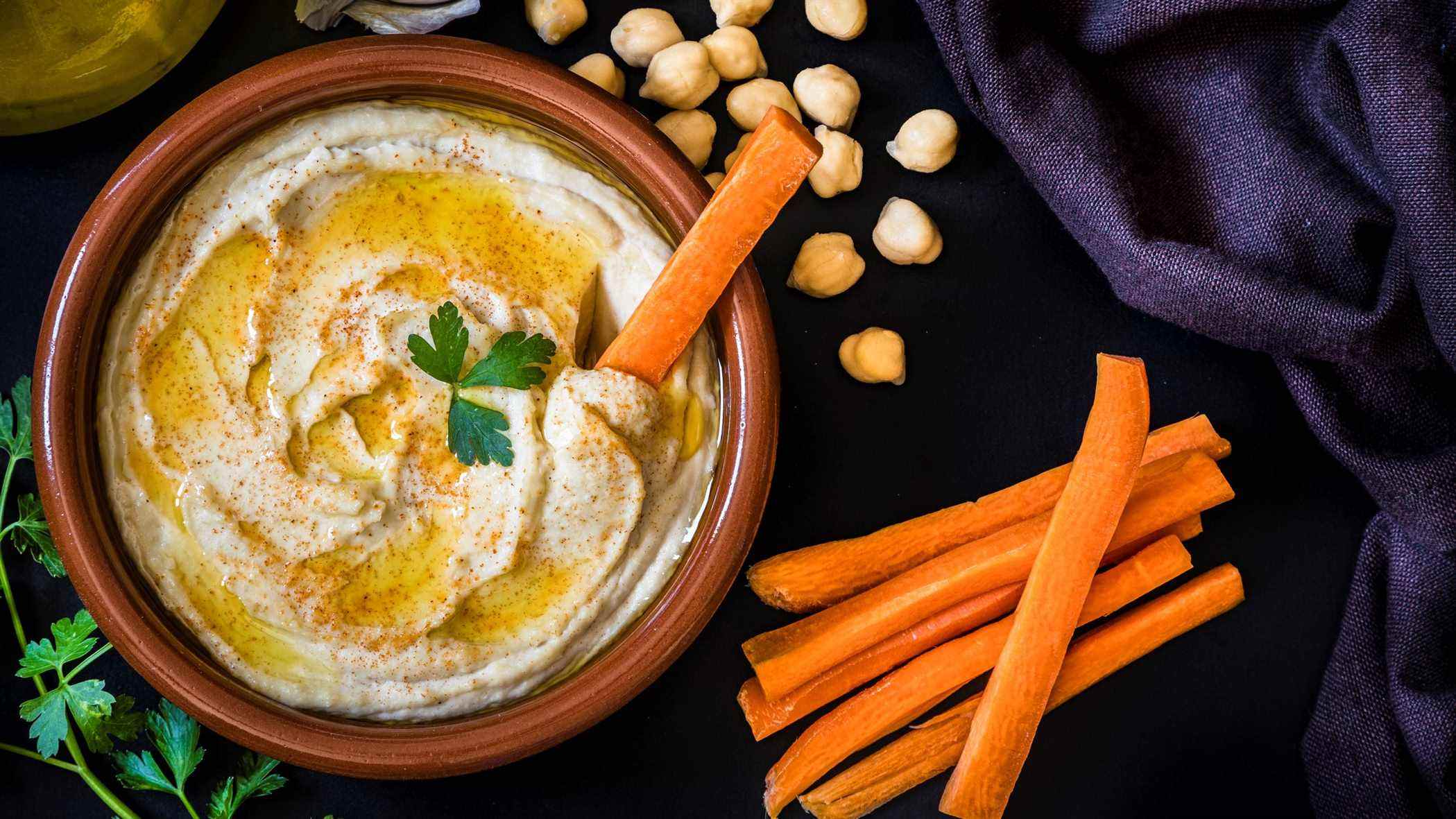 Une photo de houmous avec des bâtonnets de carottes