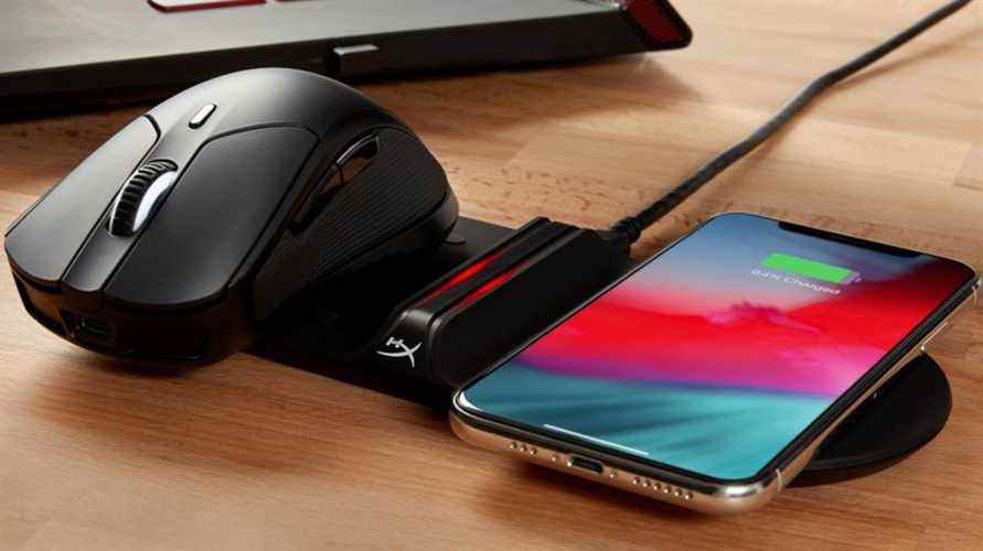 La souris de jeu sans fil HyperX Pulsefire Dart utilise sa fonctionnalité de chargement sans fil, car elle repose sur un chargeur sans fil Qi avec un smartphone à côté.