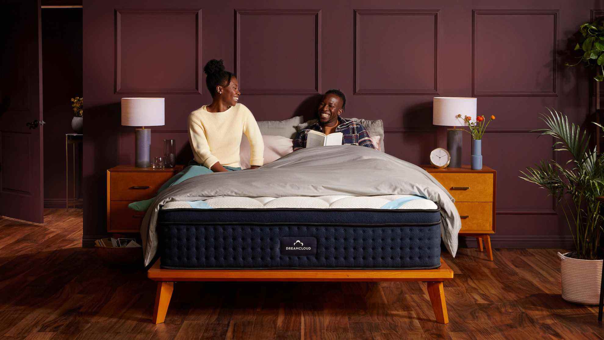 Un couple parle et rit assis sur le matelas DreamCloud Premier