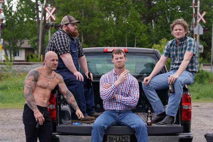 Des acteurs de la distribution de Letterkenny assis à l'arrière d'une camionnette.