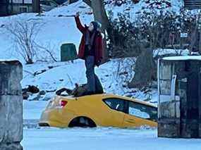 Une femme prend une photo de selfie alors qu'elle se tient au sommet d'une voiture coulée sur la rivière Rideau gelée à Manotick, Ottawa, Ontario, Canada le 16 janvier 2022, sur cette photo obtenue à partir des médias sociaux le 18 janvier 2022. Avec l'aimable autorisation de Lynda Douglas/via Reuters