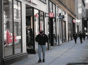 Des gens marchent le long de la rue Ste-Catherine à Montréal, à côté de magasins fermés, lors d'un verrouillage COVID-19 à Québec, le 29 décembre 2020.