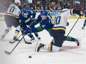 L'attaquant des Canucks de Vancouver Elias Pettersson (40) atteint autour de l'attaquant des Blues de St. Louis Ryan O'Reilly (90) en première période au Rogers Arena.