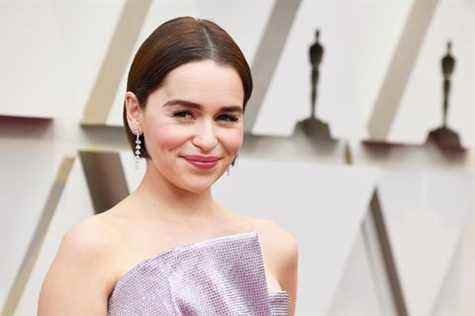 emilia clarke avec des cheveux courts bruns, des boucles d'oreilles argentées et une robe rose à paillettes