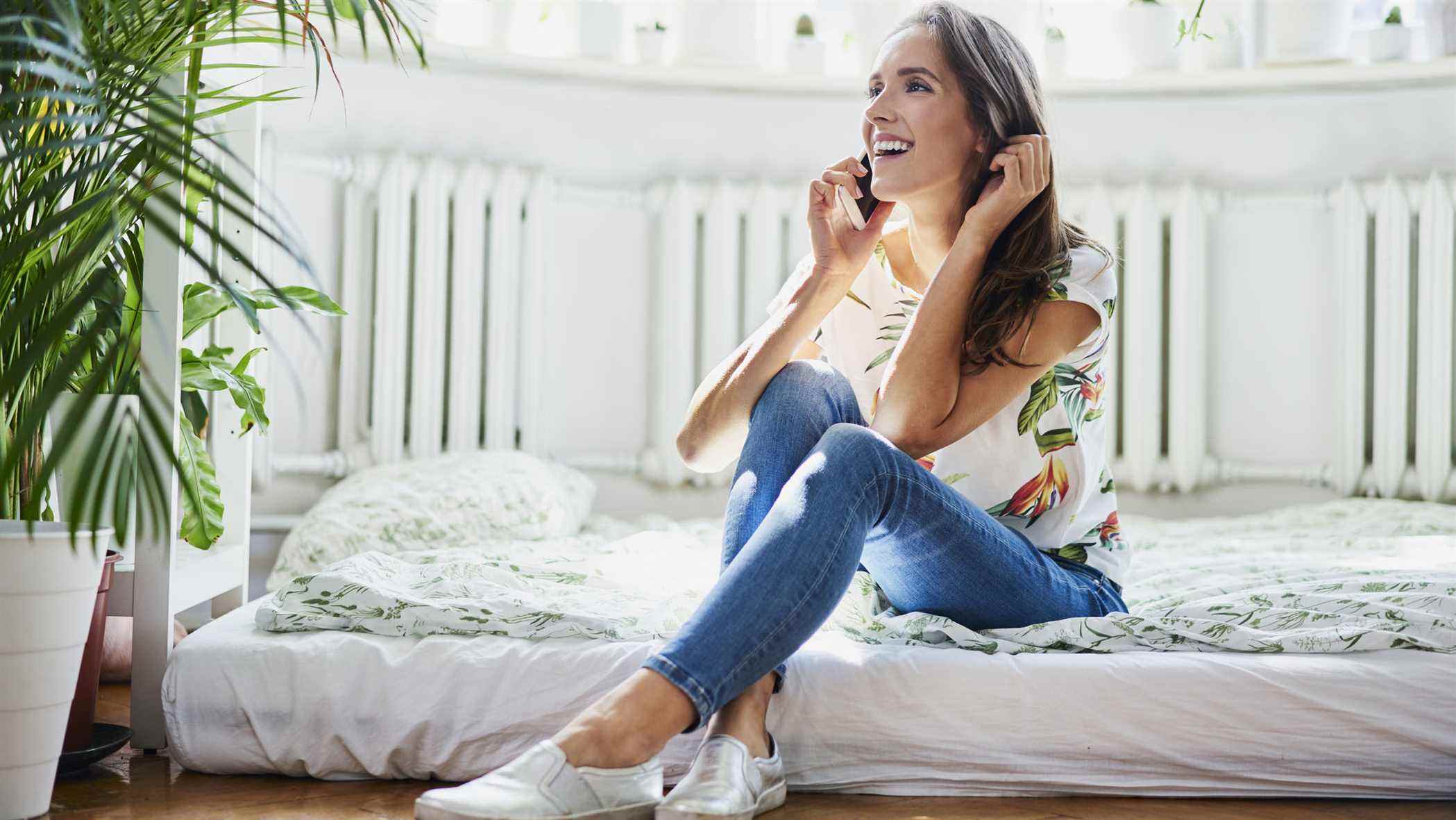 Une femme est assise sur un matelas posé directement sur le sol pour le rendre plus ferme