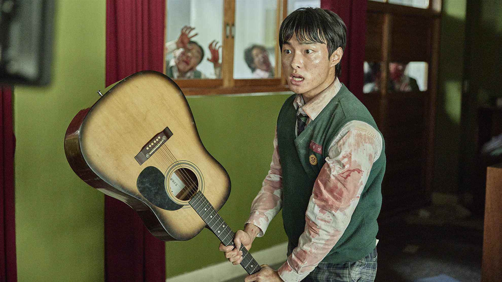 Yoon Chan-young dans le rôle de Lee Cheong-san dans Nous sommes tous morts, brandissant une guitare comme arme