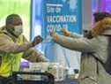 Une femme reçoit un nouveau masque au centre de vaccination COVID-19 du Palais des Congrès de Montréal le jeudi 20 janvier 2022. 