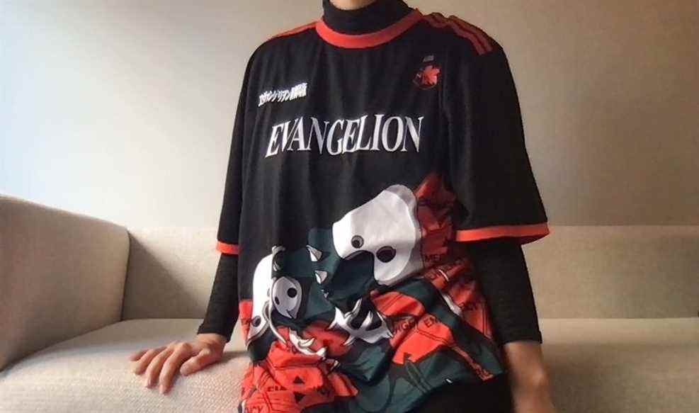 une personne est assise sur un canapé portant un ab manque et un maillot rouge evangelion 