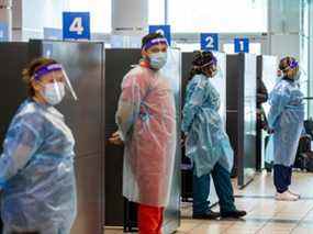 Les travailleurs de la santé se préparent à tester les passagers pour COVID-19 à leur arrivée à l'aéroport Pearson de Toronto.