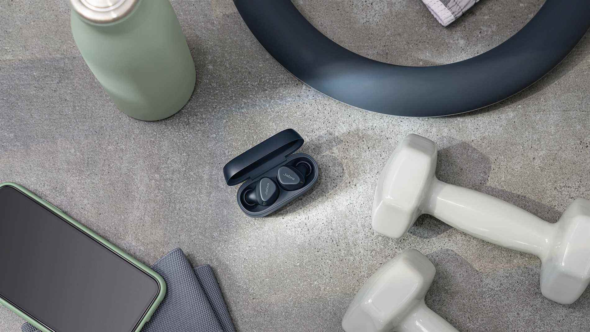 Jabra Elite 4 Active en noir dans son étui de charge, entouré d'équipements de fitness