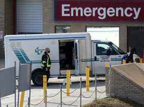 Un travailleur de la santé aide à décharger un véhicule de service de civière à l'hôpital Saint-Boniface de Winnipeg, au Manitoba.