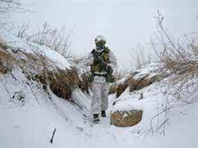 Un membre des forces armées ukrainiennes marche sur des positions de combat près de la ligne de séparation des rebelles soutenus par la Russie à l'extérieur de la ville d'Avdiivka dans la région de Donetsk, en Ukraine, le 25 janvier 2022.